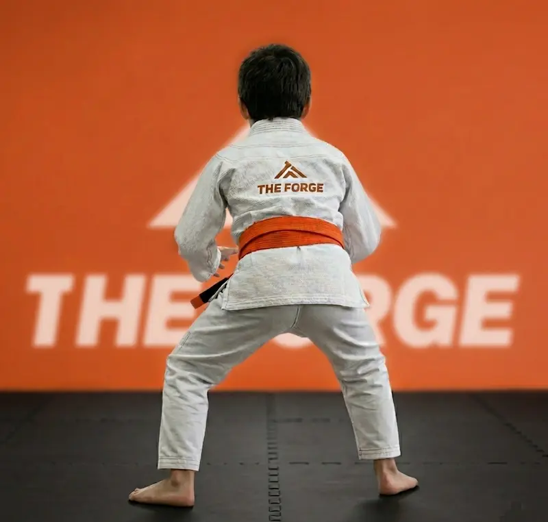 Niño concentrado en tatami durante clase de artes marciales